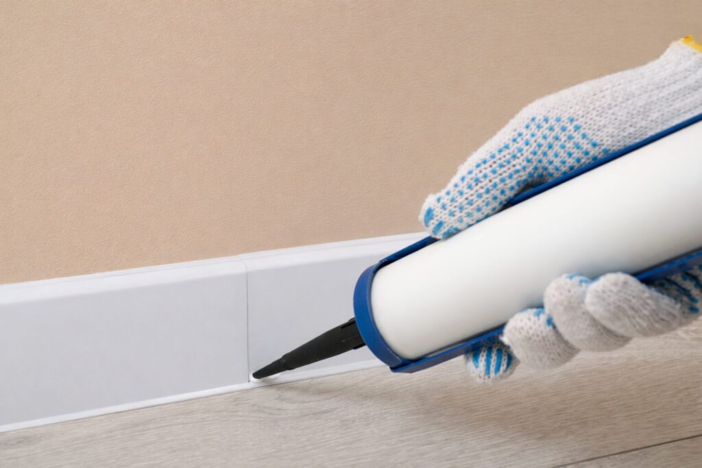 床と巾木の隙間にコーキング材を丁寧に充填している作業風景