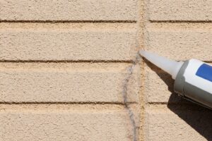 外壁のひび割れにコーキング剤を充填して補修している様子