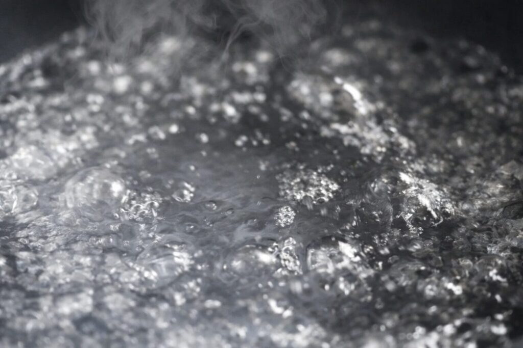 沸騰した水の表面で細かい気泡が弾け、湯気が立ち上る様子を高精細に捉えたクローズアップ画像