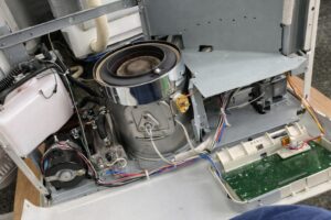 分解されたストーブ内部の構造で、燃焼部・送風ファン・基板・配線が露出している状態