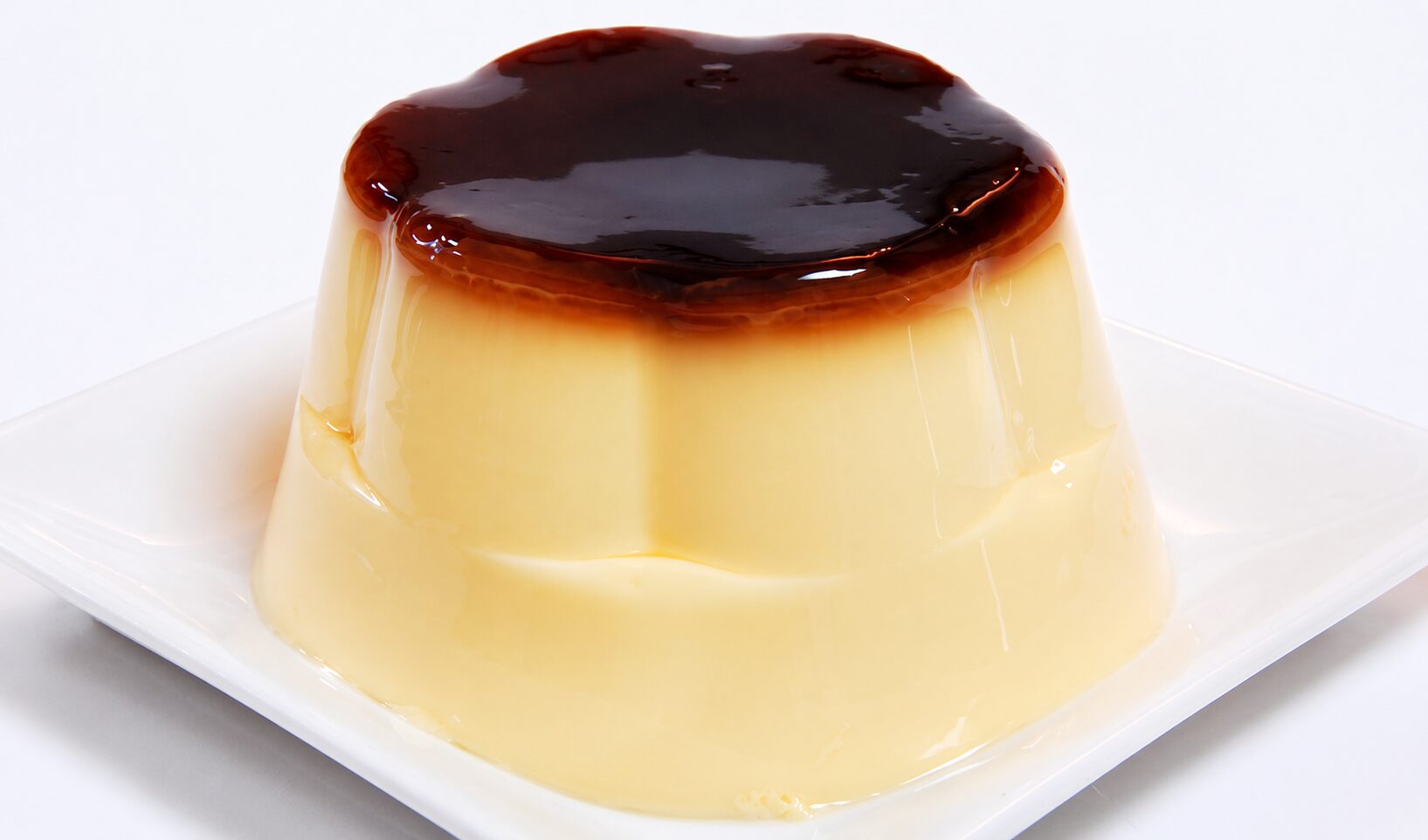 白い角皿にのせられた、カラメルソースがとろりとかかったなめらかなプリン