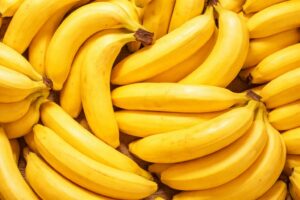 明るい照明のもとで並べられた、黄色く熟したバナナが重なり合うように配置された高画質なクローズアップ画像