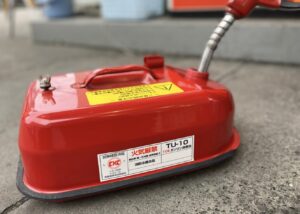 赤いガソリン携行缶に給油ノズルを差し込んでいる様子と注意ラベルが貼られている状態
