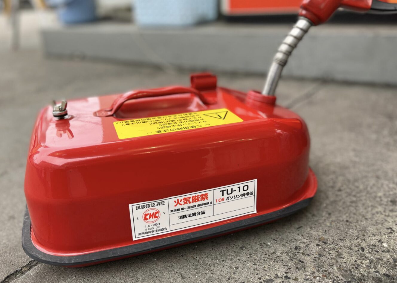 赤いガソリン携行缶に給油ノズルを差し込んでいる様子と注意ラベルが貼られている状態