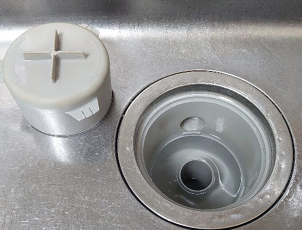 キッチンシンクの排水口に設置されたワントラップと取り外したフタの状態