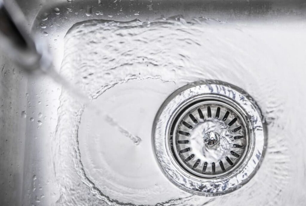 水を流して排水口周りを洗い流しているキッチンシンク