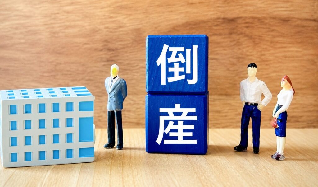 倒産を示す青いブロックとミニチュアの人物・建物が並ぶ企業経営イメージ写真
