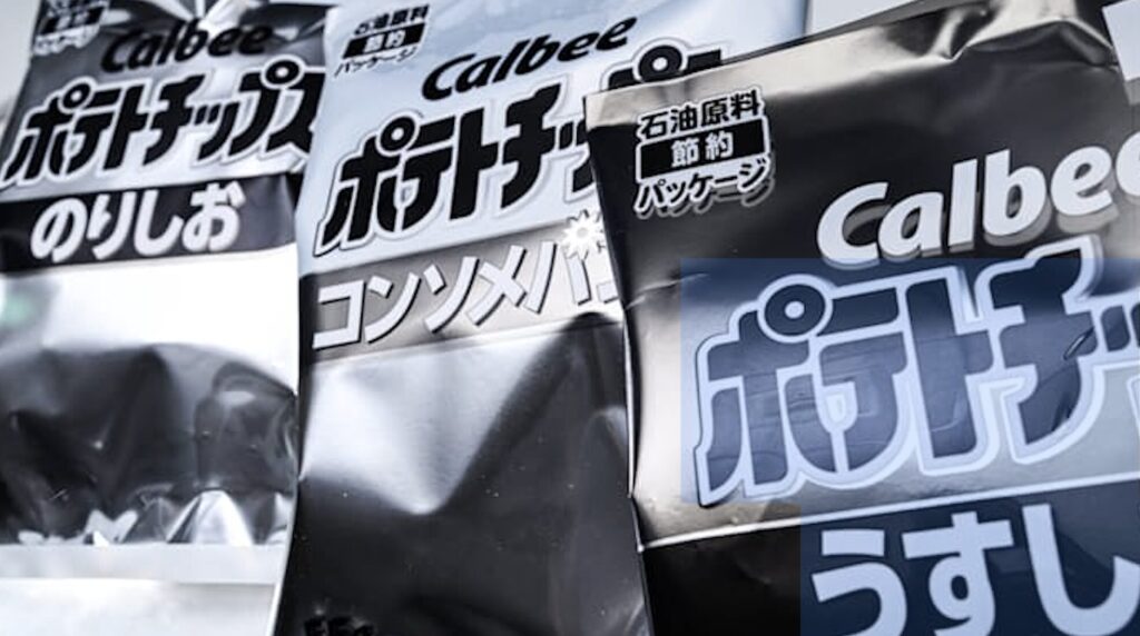 石油原料節約パッケージとしてモノクロ化されたカルビーのポテトチップス袋が並ぶ様子